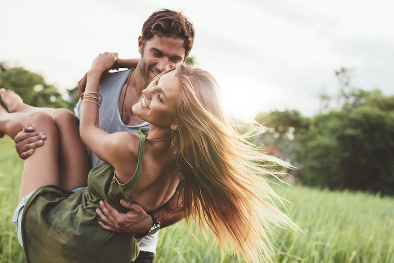 Woman being carried by her boyfriend in a field