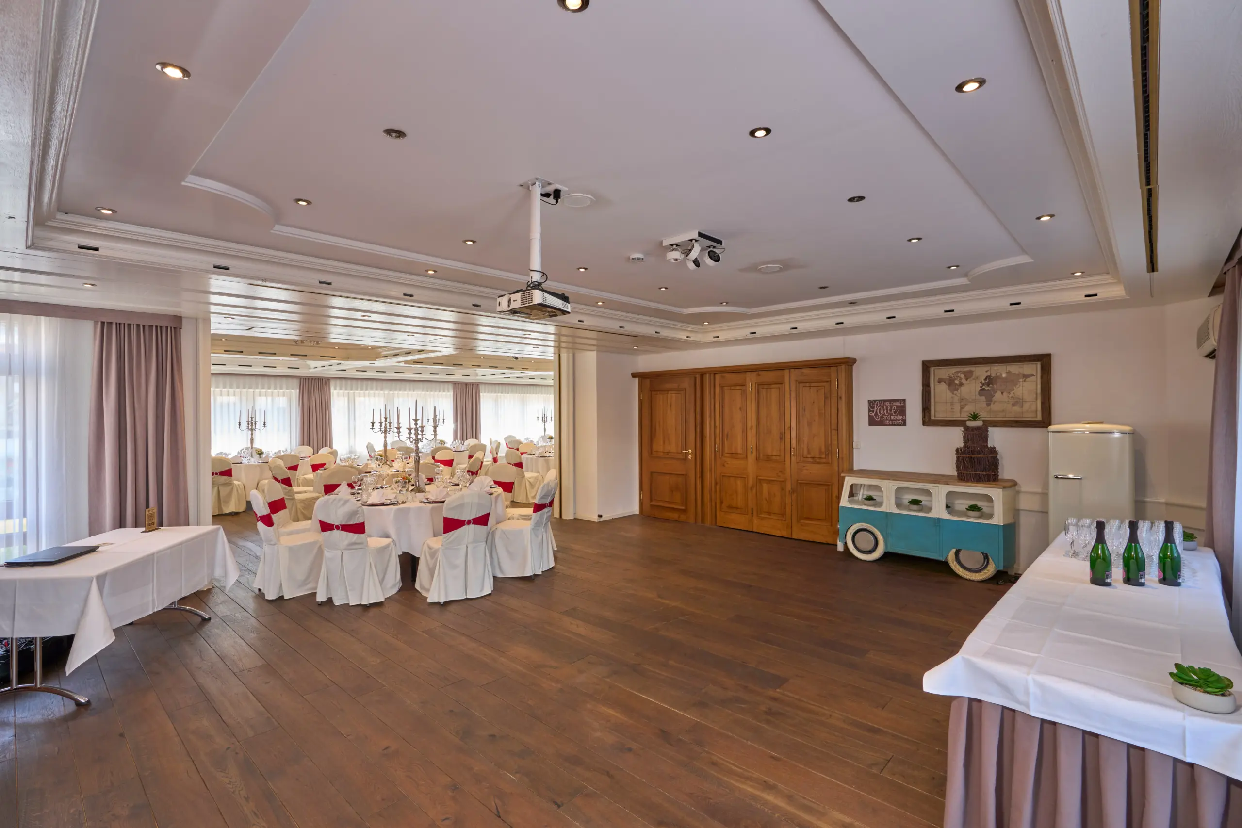 Großer Raum mit Bühne und dekorierten Tischen für Veranstaltungen